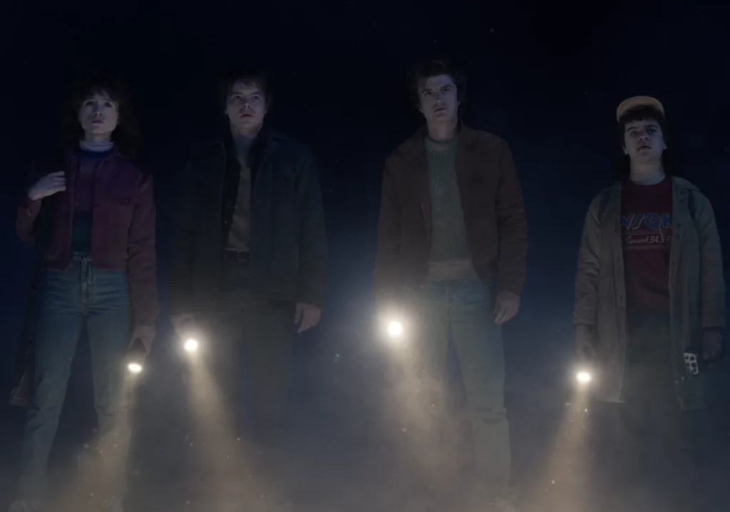 Nancy, Jonathan, Steve, and Dustin standing together looking at the Upside Down storm in Stranger Things.