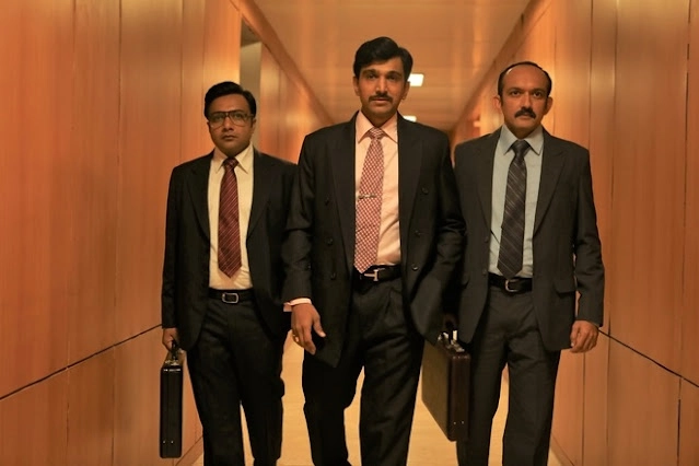 Pratik Gandhi as Harshad Mehta walking with his team in Scam 1992.