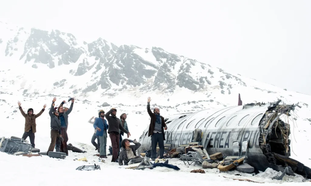 The survivors of the Andes plane crash cheering and looking up at the sky in Society of the Snow.