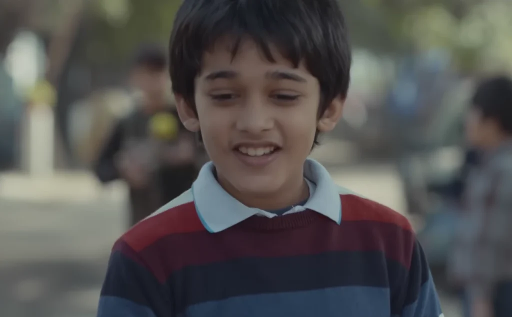 Ronit Kamra as Kittu Smiling at Newspaper - Jersey (2022) Father Son Moment Child actor Ronit Kamra smiling while looking at his father's photo in the newspaper in Jersey movie.