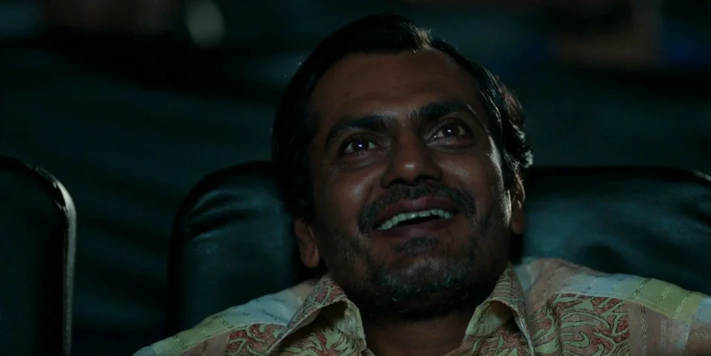 Nawazuddin Siddiqui as Liak Nawazuddin Siddiqui smiling while watching a movie in a theatre in Badlapur.